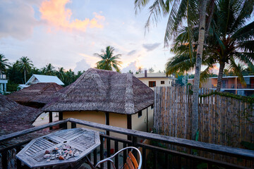 Fototapeta premium Tranquil Tropical Retreat With Palm Trees and Bamboo Fences at Sunset