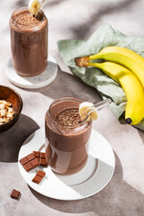 Vegetarian chocolate nuts smoothie with banana in a glass on a light  background with fresh fruits