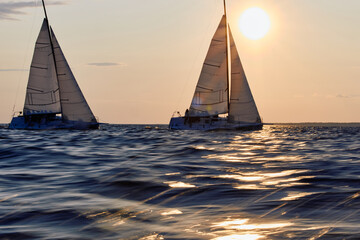 Sailing regatta in the Gulf of Finland at sunset, two sailing yachts competing in a race, splashing...