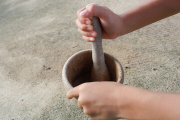A boy's hand is holding a wooden mortar and pestle.