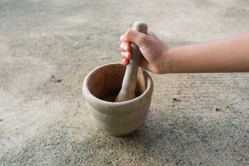 A boy's hand is holding a wooden mortar and pestle.