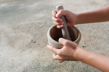 A boy's hand is holding a wooden mortar and pestle.