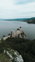 Naklejka premium Aerial view of Golubac Fortress on rocky cliff above the Danube River in Serbia, surrounded by water and medieval towers. The most popular and beautiful fortress in Serbia on the border with Romania