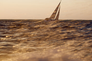 Sailing regatta in the Gulf of Finland at sunset, sailing yacht competing in a race, splashing...
