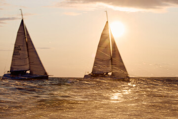 Sailing regatta in the Gulf of Finland at sunset, two sailing yachts competing in a race, splashing...