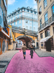 Happy Young Couple Running On The Pink Street In Lisbon, Portugal