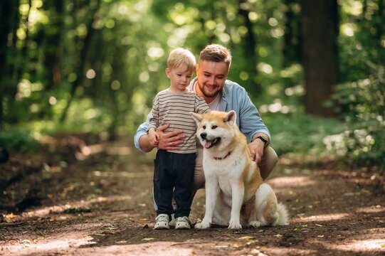 Sitting, playing with pet. Father with son and dog are in the forest