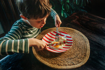 Young European Boy Eating Fried Egg at Breakfast
