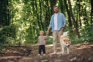 Free time, having a walk, wellness. Father with son and dog are in the forest