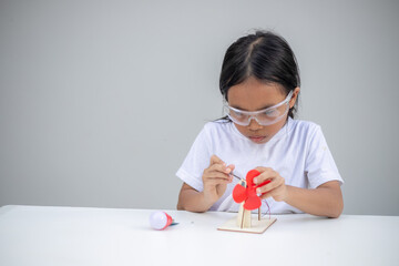 A young girl explores renewable energy outdoors by playing with a wind turbine toy