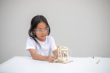 A young girl learns basic engineering by playing with a hydraulic excavator toy
