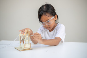 A young girl learns basic engineering by playing with a hydraulic excavator toy