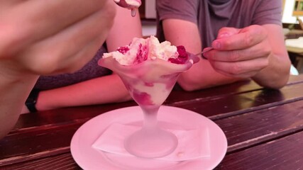 Indulging in a delicious dessert treat at Ritzaualm in Tyrol during summer, a couple enjoy an ice cream with cream and raspberries