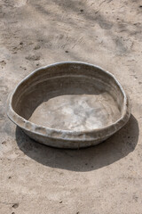 Weathered dented gray aluminum basin on concrete floor