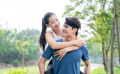 Fototapeta premium Couple having fun Woman embracing man who is giving her a piggyback ride in outdoor setting