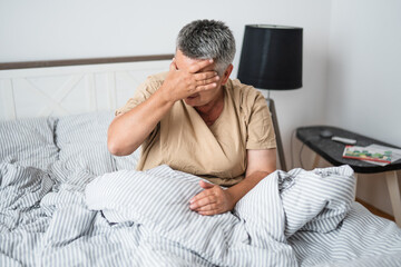 Obraz premium Mature woman waking up with headache in the morning in the bedroom. 