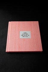 Photobook, photo album in pink leather cover on black background with metallic shield, inscription...