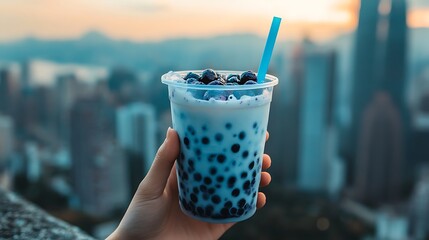 Cropped hand lifting blueberry vanilla boba from stone ledge with blurred city backdrop