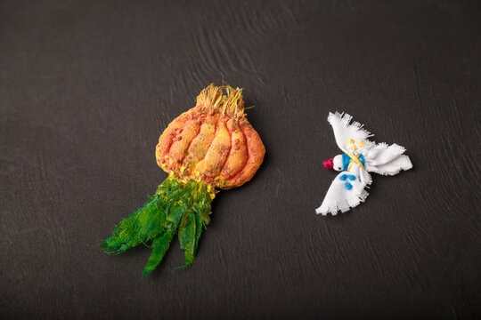 Two brooches made from cotton fabric on black background. Green onion and peace dove pins as Ukrainian symbols of peace, agriculture