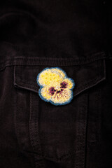 Pansy, heartsease embroidery brooch with beads on black jeans fabric background, closeup shot, copy...