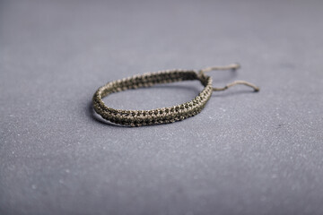 Macrame yarn friendship bracelet, wristband on grey background. Soft focused shot, copy space