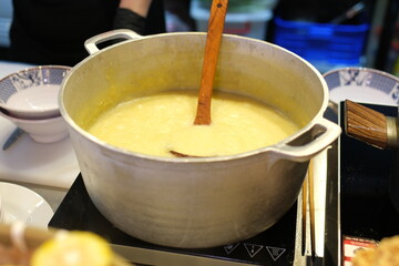 A large cooper pot of corn porridge is boiling over a fire close up. High quality 4k footage