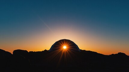 Sunrise through dome tent on rocky outcrop
