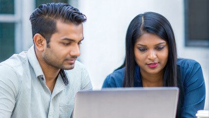 Busy colleagues collaborating on business task using laptop at shared desk


