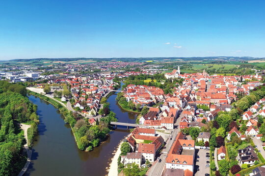 Luftaufnahme von Donauw&ouml;rth mit roten D&auml;chern, historischen Geb&auml;uden und einem markanten Turm, eingebettet in eine gr&uuml;ne Landschaft. Die Stadt bietet eine charmante Kulisse.
