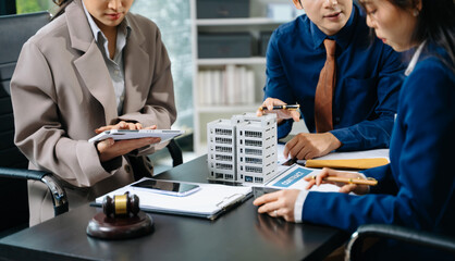 Business team consulting on real estate deal with building model, contract, and calculator. Ideal...