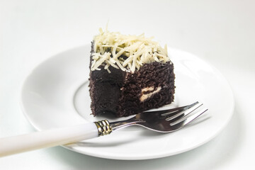 a piece of chocolate cake on a plate with a fork isolated on a white background