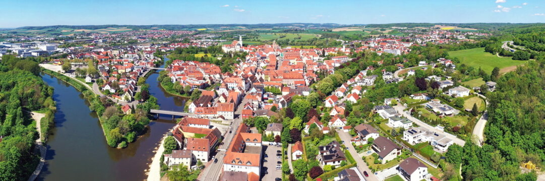 Luftaufnahme von Donauw&ouml;rth mit roten D&auml;chern, historischen Geb&auml;uden und einem markanten Turm, eingebettet in eine gr&uuml;ne Landschaft. Die Stadt bietet eine charmante Kulisse.