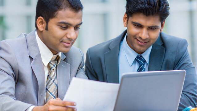 Indian employees in business attire reviewing timeline and charts on laptop


