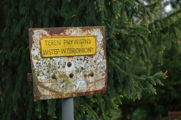 A rusty metal sign with an inscription in Polish, translation: private property, no entry.