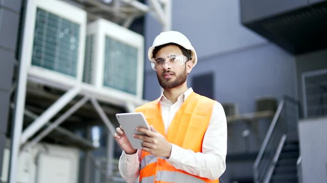 Professional engineer wearing safety helmet and vest standing at the factory and working on a digital tablet. Confident industry manager inspector specialist in uniform works on checking production