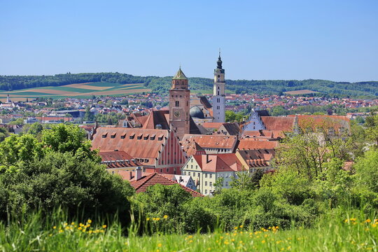Luftaufnahme von Donauw&ouml;rth mit roten D&auml;chern, historischen Geb&auml;uden und einem markanten Turm, eingebettet in eine gr&uuml;ne Landschaft. Die Stadt bietet eine charmante Kulisse.