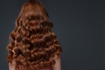 Fototapeta premium Teenage girl with healthy wavy hair on dark grey background, back view. Space for text