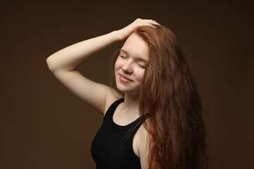 Fototapeta premium Beautiful teenage girl with healthy wavy hair on brown background