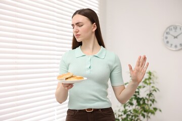 Gluten free diet. Young woman refusing pretzels indoors