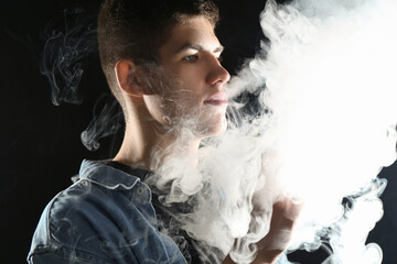 Man using electronic smoking device on black background