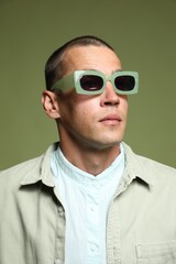 Obraz premium Fashionable portrait of handsome man in stylish outfit on green background