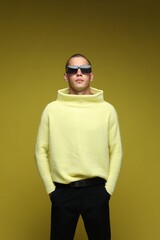 Fashionable portrait of handsome man in stylish outfit on olive background