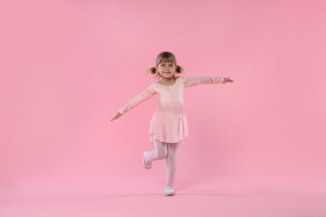 Cute little girl dancing on pink background