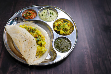 Crispy Masala dosa is a popular South Indian food item served with tomato chutney, coconut chutney, spicy potato masala, or aloo ki sabzi and sambar. Copy space. Crunchy Rice crepes.