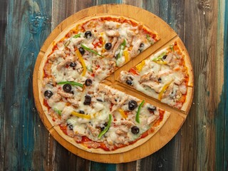 Delicious Thin Crust Chicken Pizza with Olives and Bell Peppers on Wooden Board – Overhead View