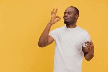 Young man showing delicious gesture on yellow background