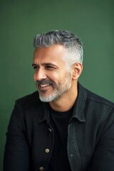Green solid background. A midlife man posing for a portrait. Modish men's fade haircut - midlife middle eastern man with short hair. Visual idea of style for aging men.