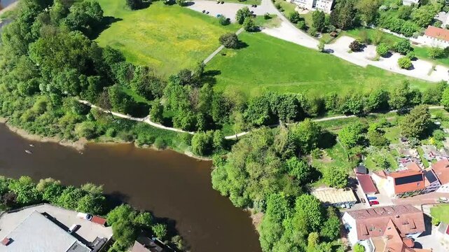 Luftaufnahme von Donauw&ouml;rth mit roten D&auml;chern, historischen Geb&auml;uden und einem markanten Turm, eingebettet in eine gr&uuml;ne Landschaft. Die Stadt bietet eine charmante Kulisse. 