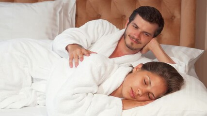 Charming couple peacefully sleeping together in a cozy hotel bed