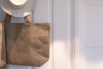 Brown female natural tote bag hanging on the wooden wall background. Reusable handbag from recycle sack material showing in bag store with copy space for product mockup.